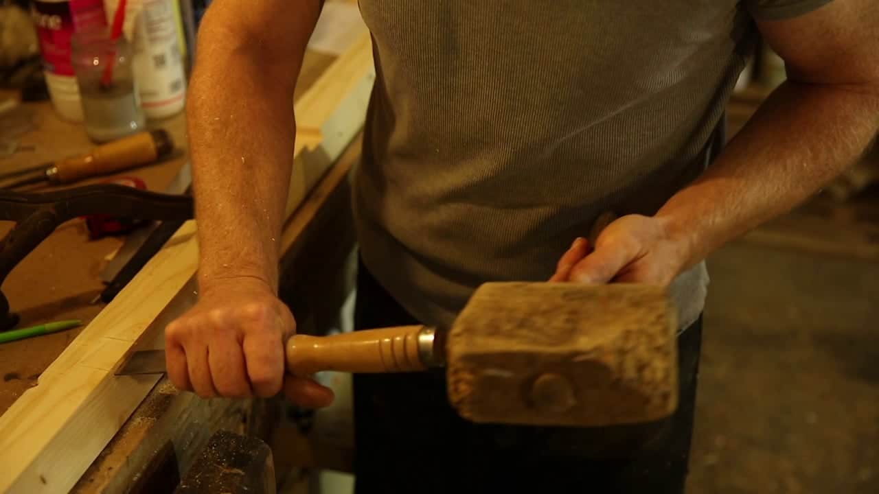 un menuiser en train de mortaiser