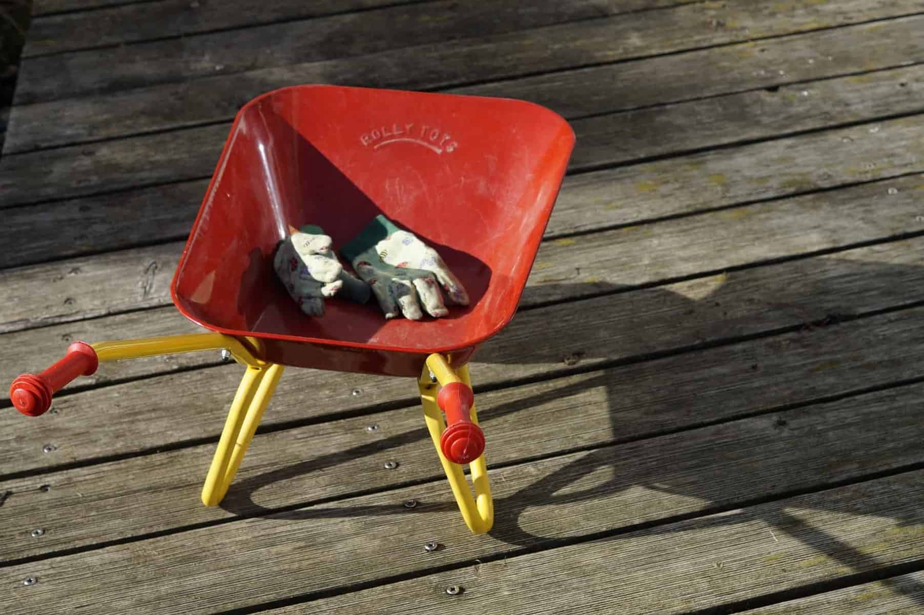 Illustration. Une petite brouette et des gants de jardinage.
