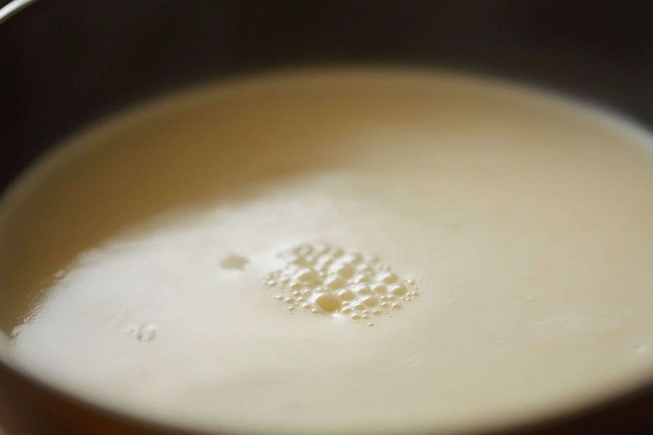 Image d'illustration. Gros plan d une casserole avec une couche lisse sur le lait chaud